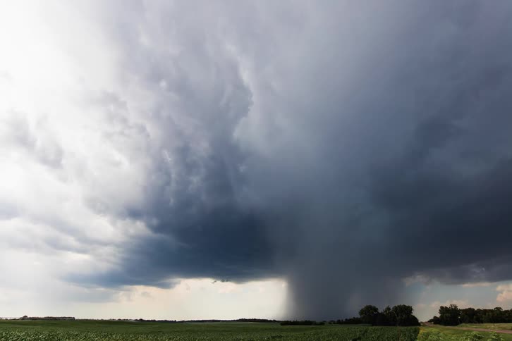 Dark storm clouds float in the sky over the field