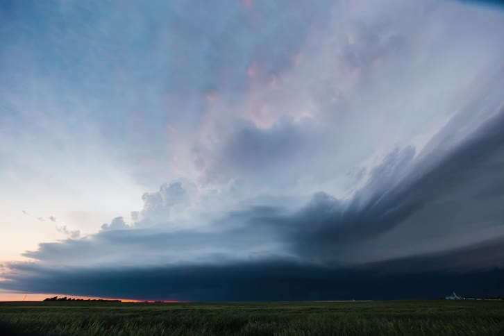 A wide shot of a monster supercell against a green field