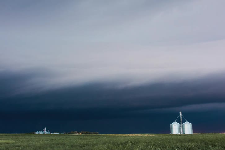 Landscape and silos of dark storm clouds and lightning