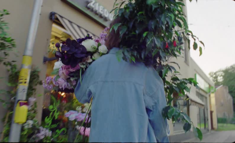 A female small business owner puts floral arrangements on display outside a florist shop