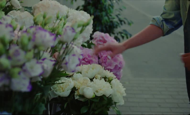 A woman is watering flowers in a suburban area