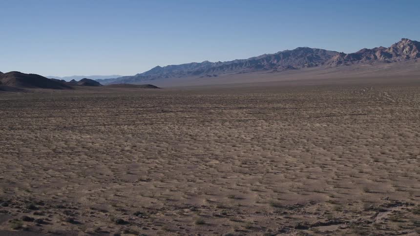 Passing over a desert landscape at the foot of a mountain range