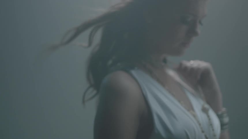 A woman touches her necklace as her hair blows
