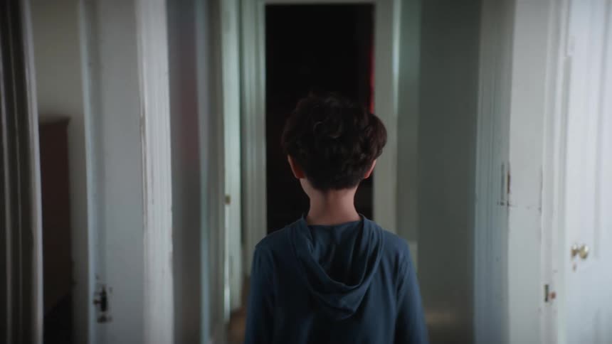 A boy is walking through the hallway in his house