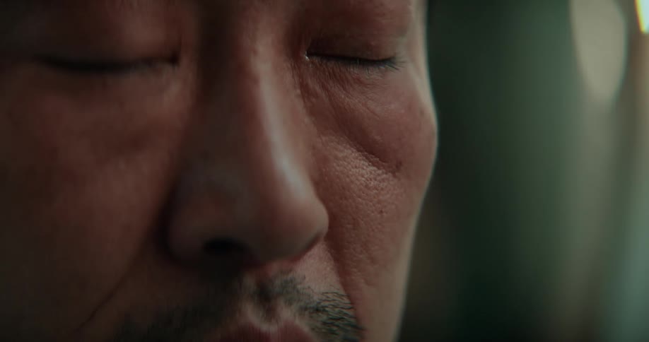 A man puts his finger under his eye and pulls down the skin and then closes his eyes
