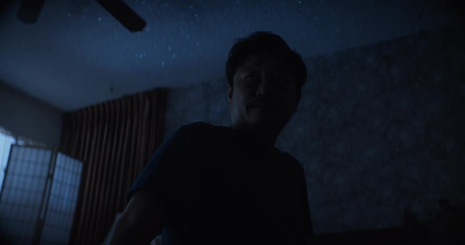 A man sitting up on his bed