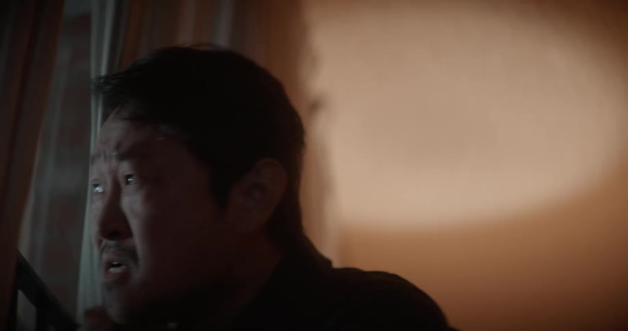 Nervous man with black shirt looks out the window