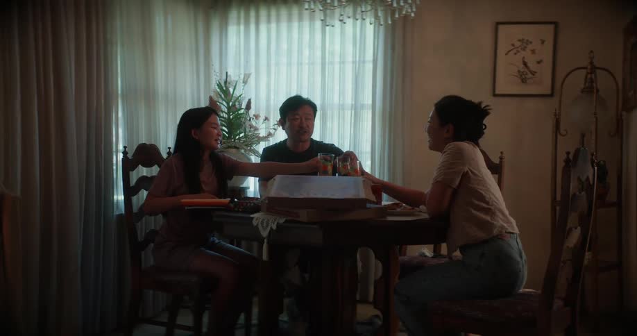 Family eats pizza at dining table in home