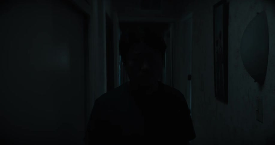 Man walking along dark hallway is silhouetted at building