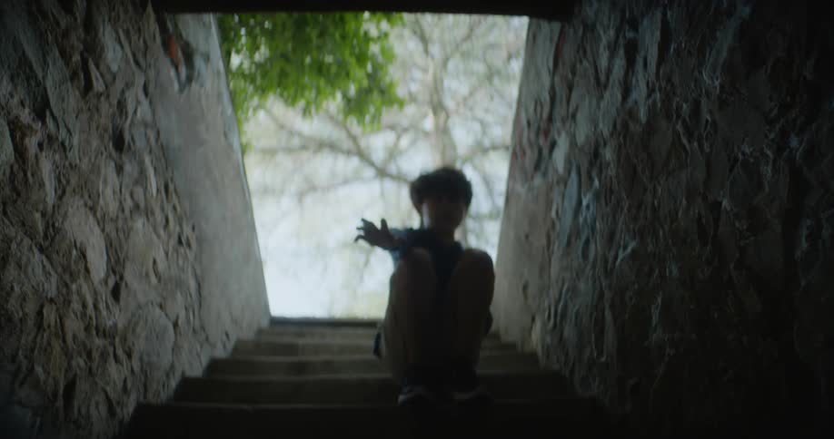 A mother reaches for her son as he looks down the stairs