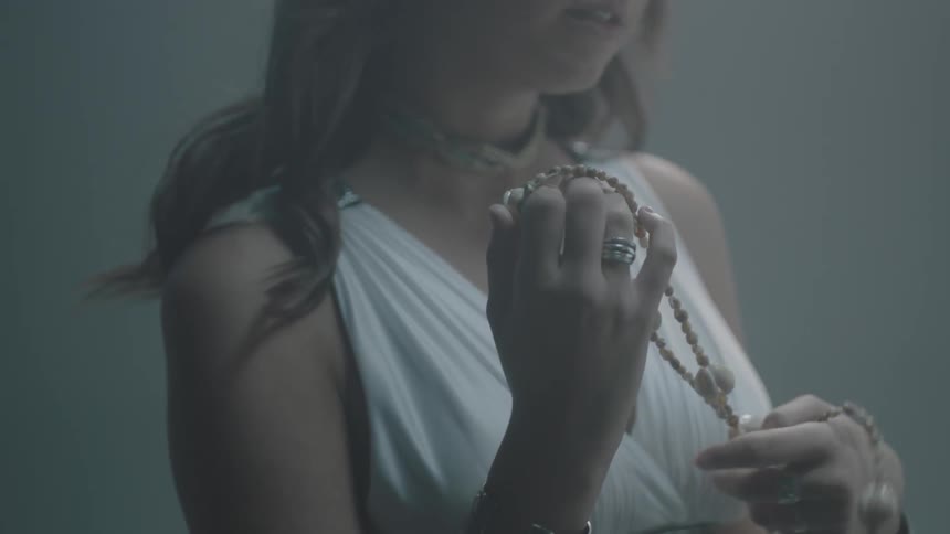 A woman twists a shell necklace around her hands