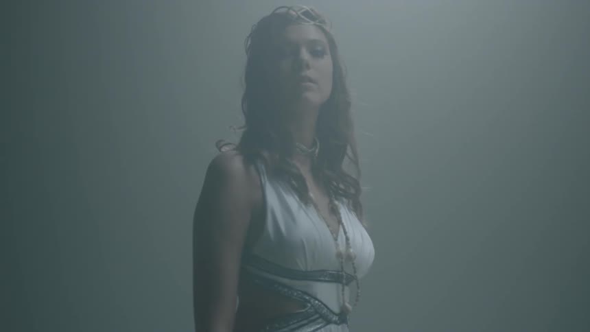 A woman in a white dress looks up