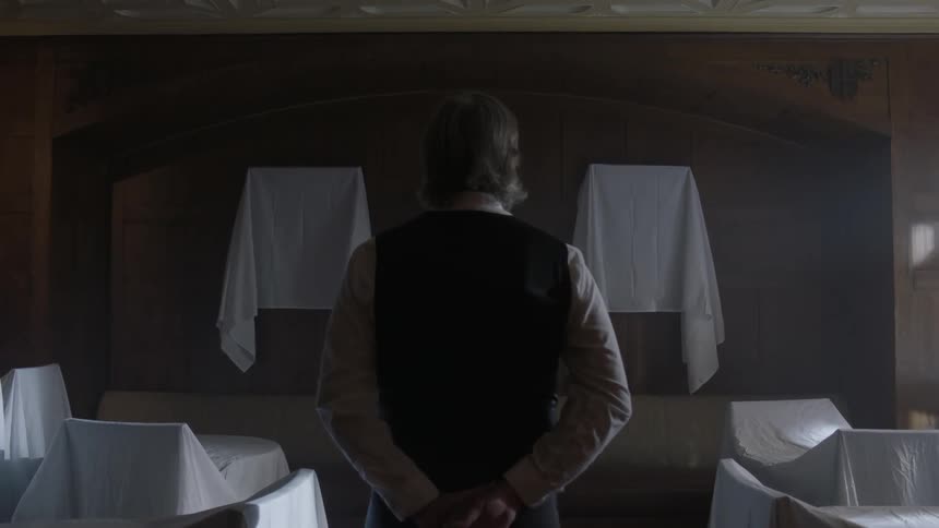 A man stands in front of covered pictures
