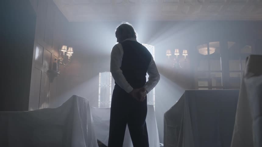 A man stands in a room with light shining on him