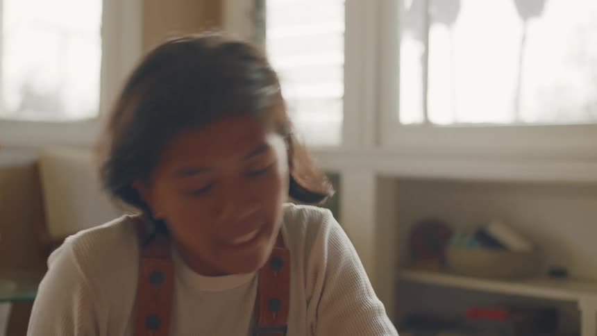 A young woman shuts her laptop while frowning and getting up from the living room floor