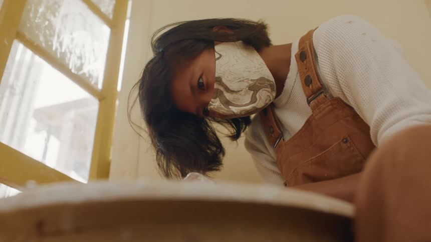 A young woman at home bends over a table as she looks at something