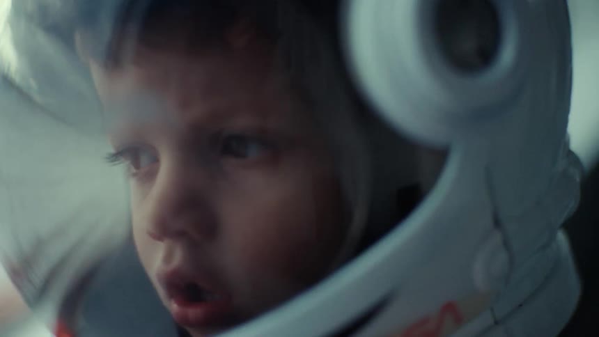 A young child is wearing an astronaut helmet as they look around