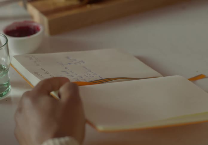 A man is holding a book and a woman points to something on the page with her pinky finger