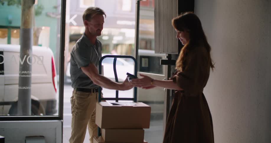 A man has a woman sign for packages he delivered to her business