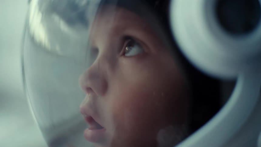 A young child is wearing an astronaut helmet as they look up