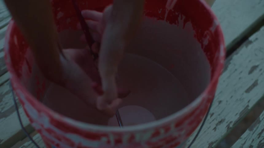 A person dipping a pot into glaze