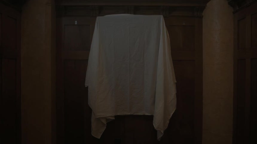 A sheet is covering something hanging on the wall