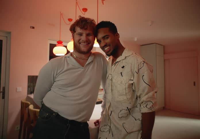 A couple pose together while standing in their kitchen