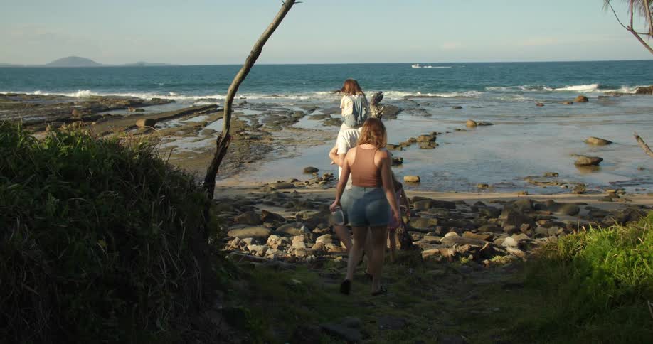A man carries his daughter on his back while the family walking to the beach
