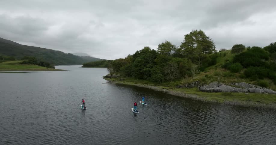Three people standup paddleboarding by a green island on the water