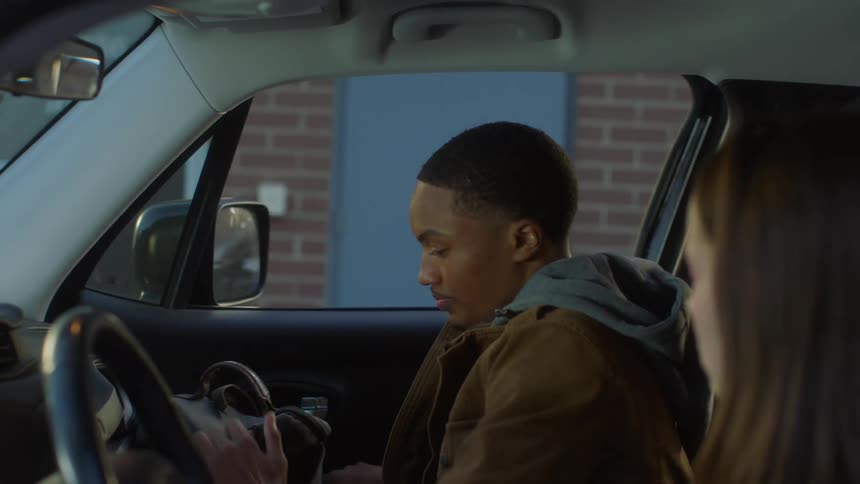 A young man gets into a car and speaks with the driver