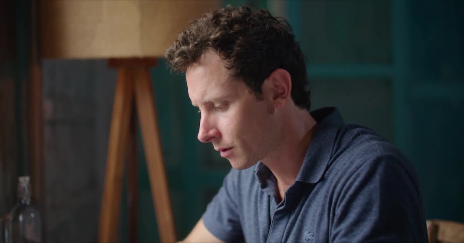 A man typing on his laptop looking contemplatively and almost stressed