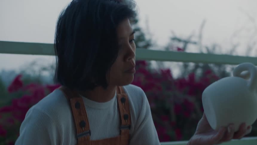 A woman on her balcony wipes the bottom of pottery