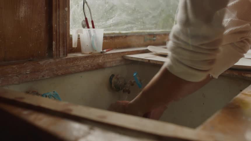 A woman squeezes out a towel that she washed in the sink