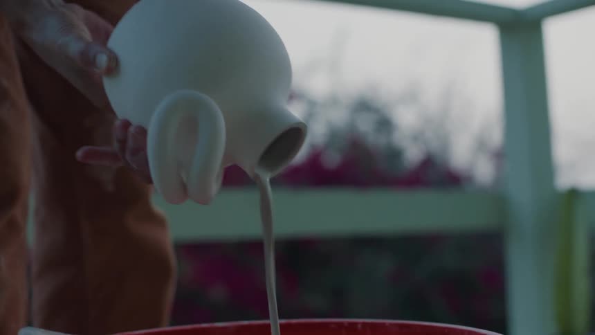 A woman pours liquid from a freshly glazed pot