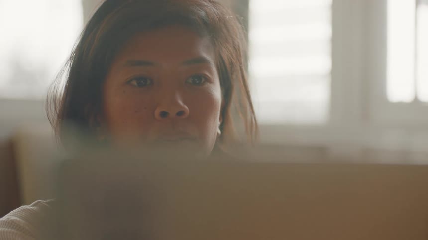 Woman at home lifts lid of laptop