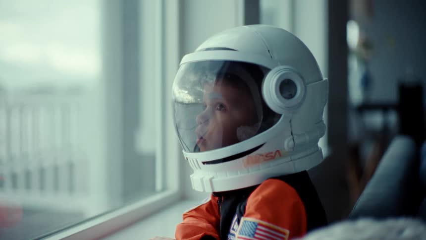 A child with an astronaut helmet on dreams of going to space