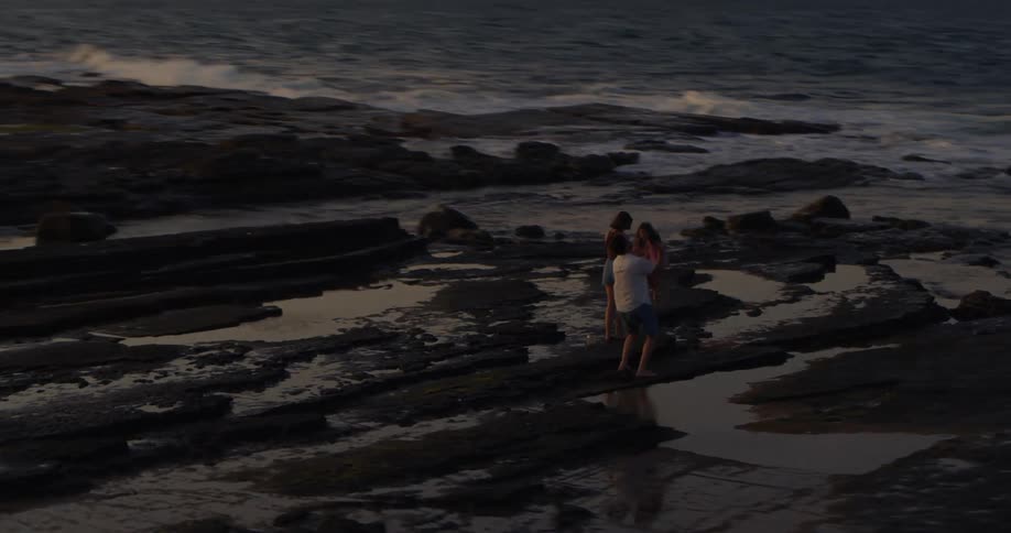 Aerial view of mother father and daughters on muddy beach next to the ocean at dusk