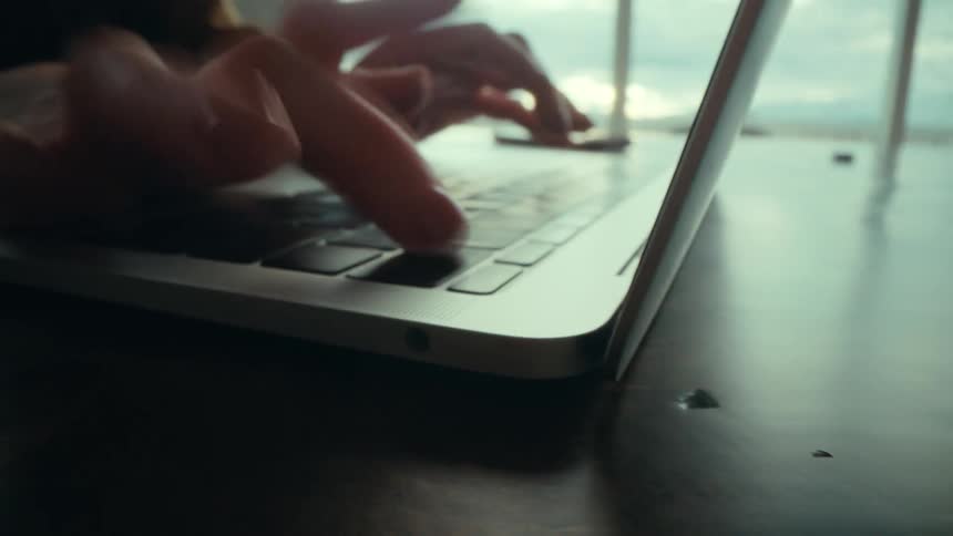 An up close of a persons fingers typing on a laptop keyboard