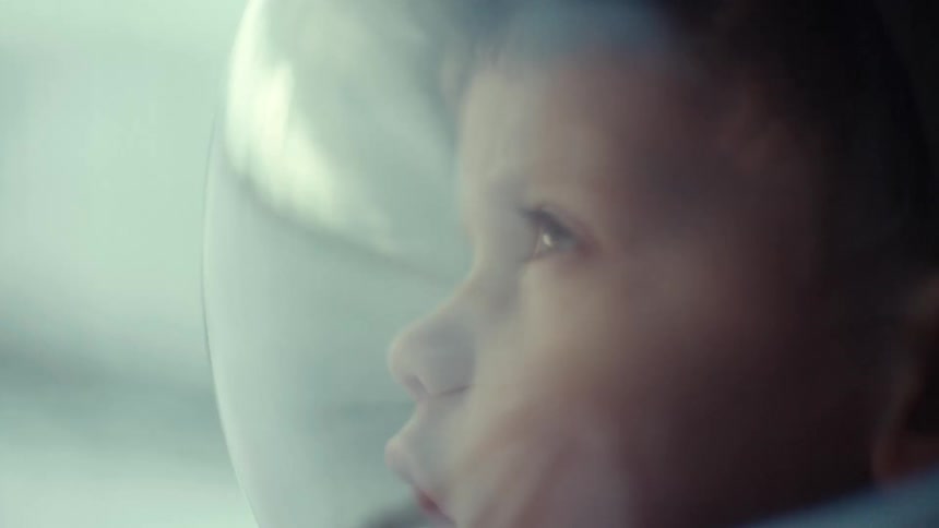 Boy wears astronaut helmet and looks up