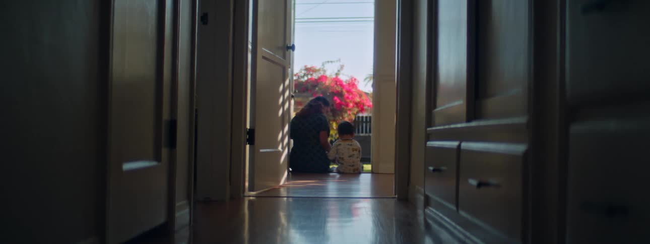 A woman sits at the end of a hallway with her son