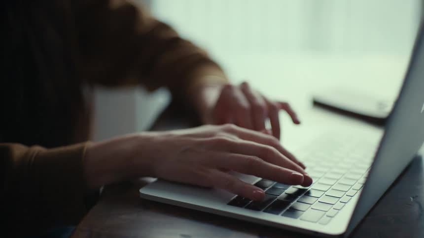 A woman using her laptop scrolling with her fingers and looking at the screen