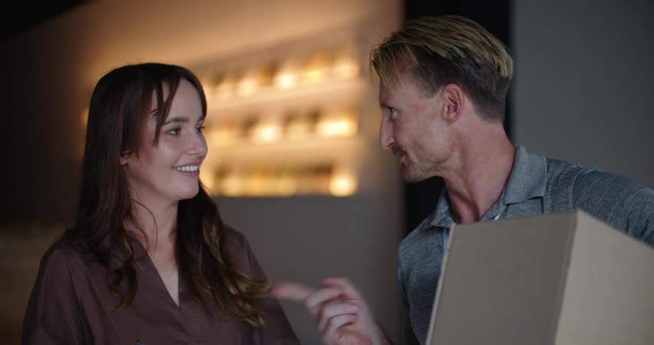 A man holding boxes while a women signs and they talk and smile