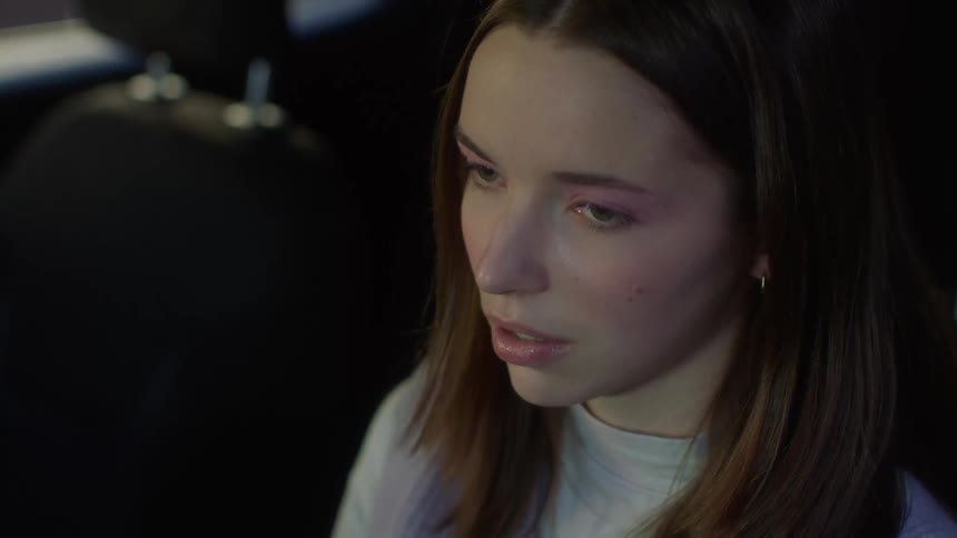 Woman with brown hair and gray shirt sighs in exasperation in car