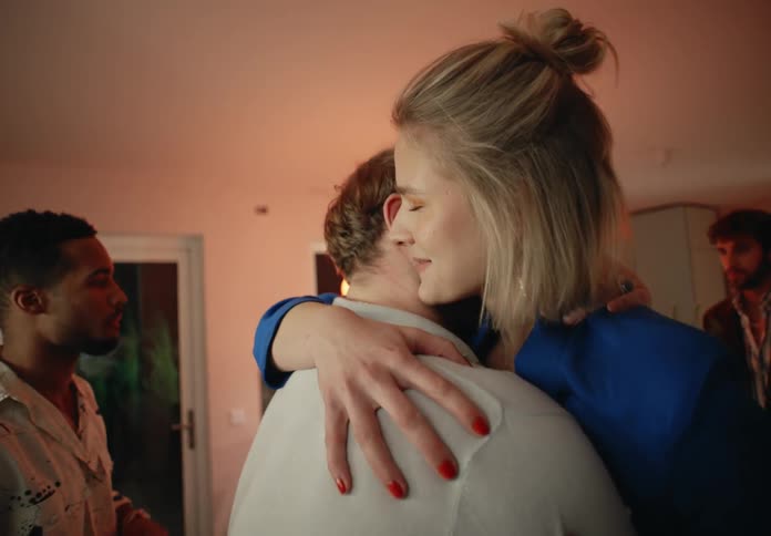 A man with a beard hugs a woman wearing a blue top