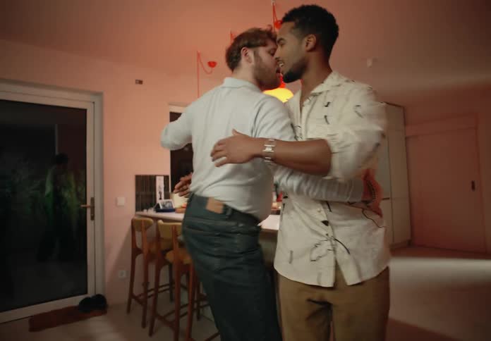 Two men smile while dancing close together in home at night