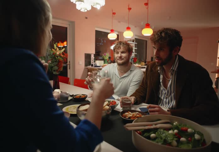 Gay and straight couples sitting at table have dinner and talk to each other at home