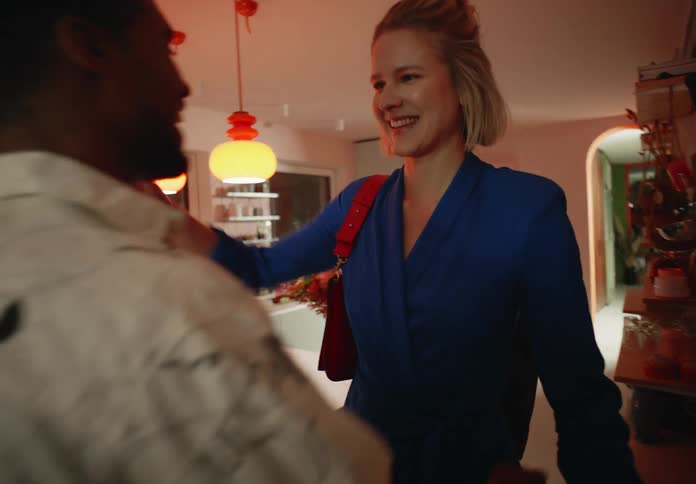 Two people enter a kitchen and hug two people already in the kitchen
