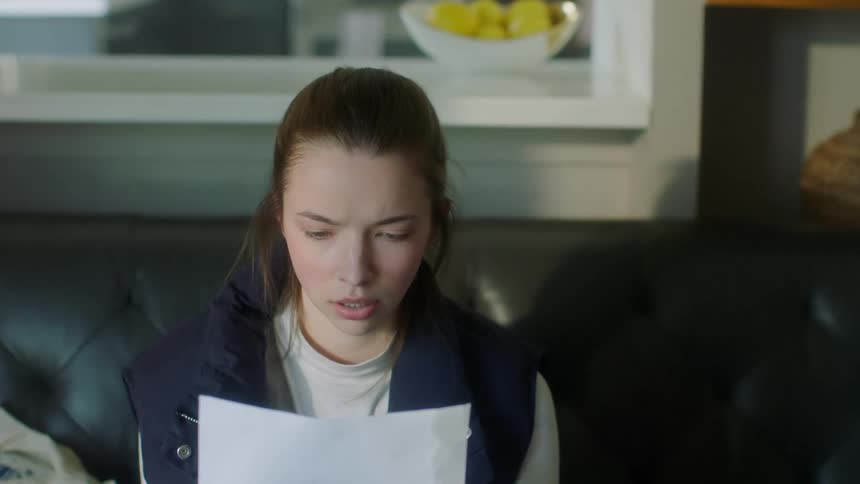 Woman smiles as she reads letter then looks disappointed