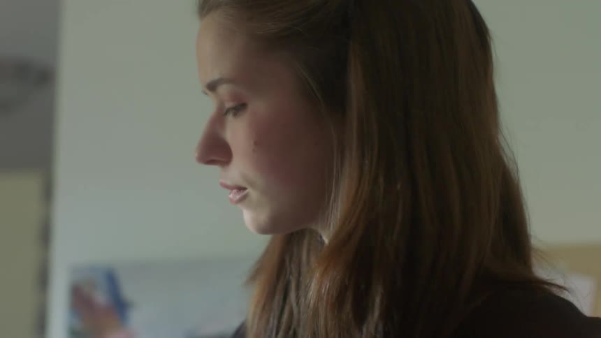 A teenage girl is standing in a room looking ahead and thinking