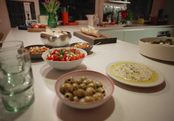 Person picks up salad from collection of prepared dishes sitting on kitchen counter
